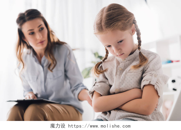 心情不好的小女孩被一个美女在开导成人心理学家与抑郁的孩子交谈交叉的手臂